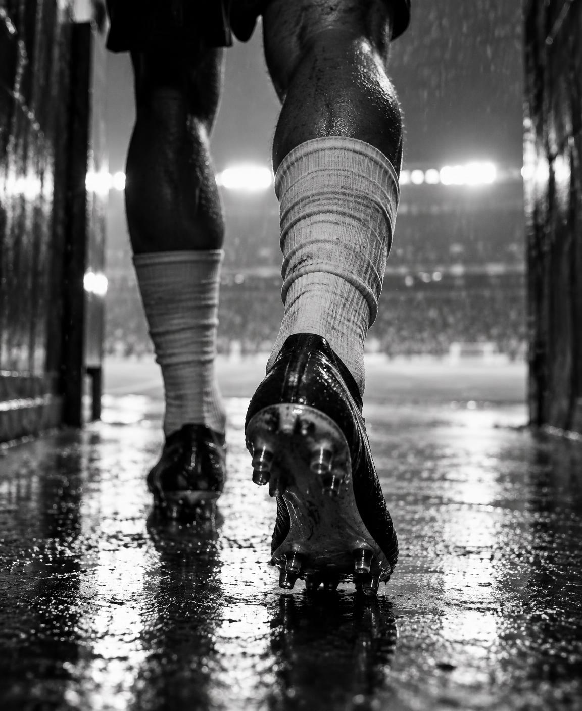 Footballer walking through a rain-soaked tunnel